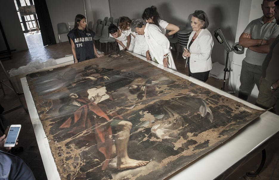 Carabinieri and others examining a damaged Guercino canvas