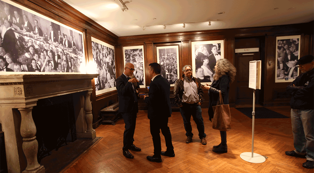 Visitors in the Casa Italiana gallery discuss the historical photos of the 1927 inauguration dinner.
