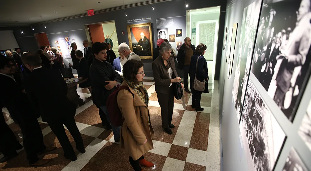 Crowd examining with interest the photographs on the wall of the gallery.