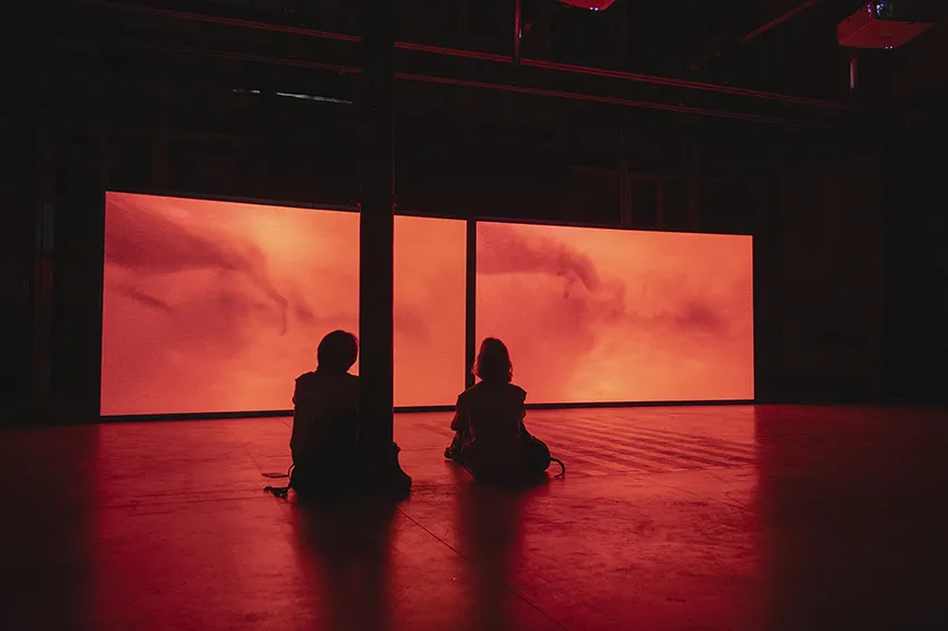two people sitting in front of orange screen projections